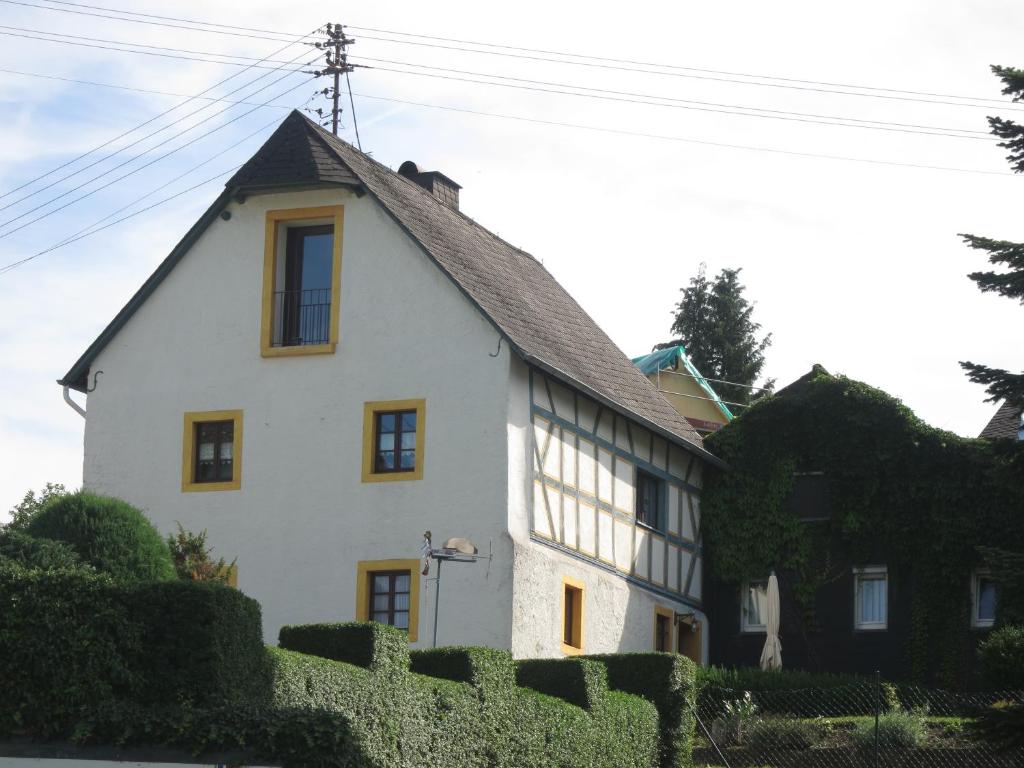 ein weißes Haus mit schwarzem Dach in der Unterkunft Ferienwohnungen Haus Hinneres in Schalkenmehren