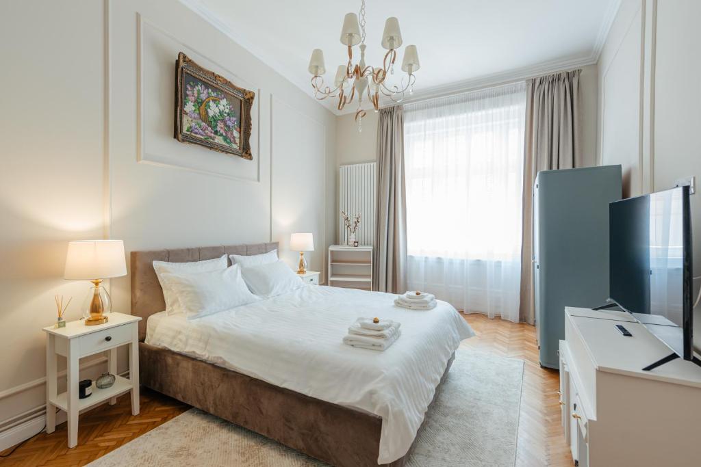a white bedroom with a bed and a television at Old Town Square Apartments Cluj in Cluj-Napoca