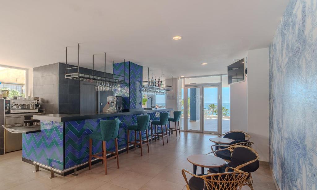 a kitchen with a bar with chairs and tables at Spirit Hotel Benalmadena Beach in Benalmádena