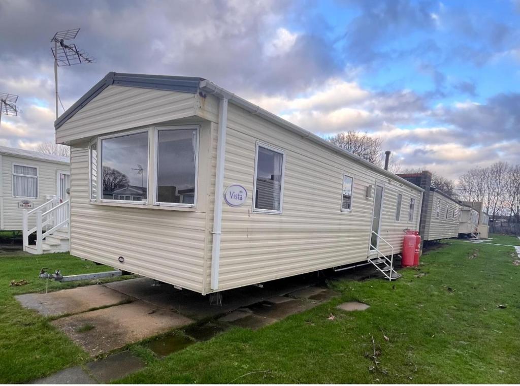 a white mobile home is parked in a yard at 3 Bedroom Caravan - Sleeps 8 - Parking Wifi Pool in Clacton-on-Sea