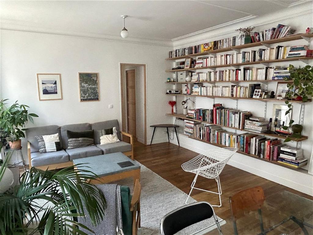 - un salon avec un canapé et une étagère avec des livres dans l'établissement Bel appartement quartier de la Roquette by Weekome, à Paris