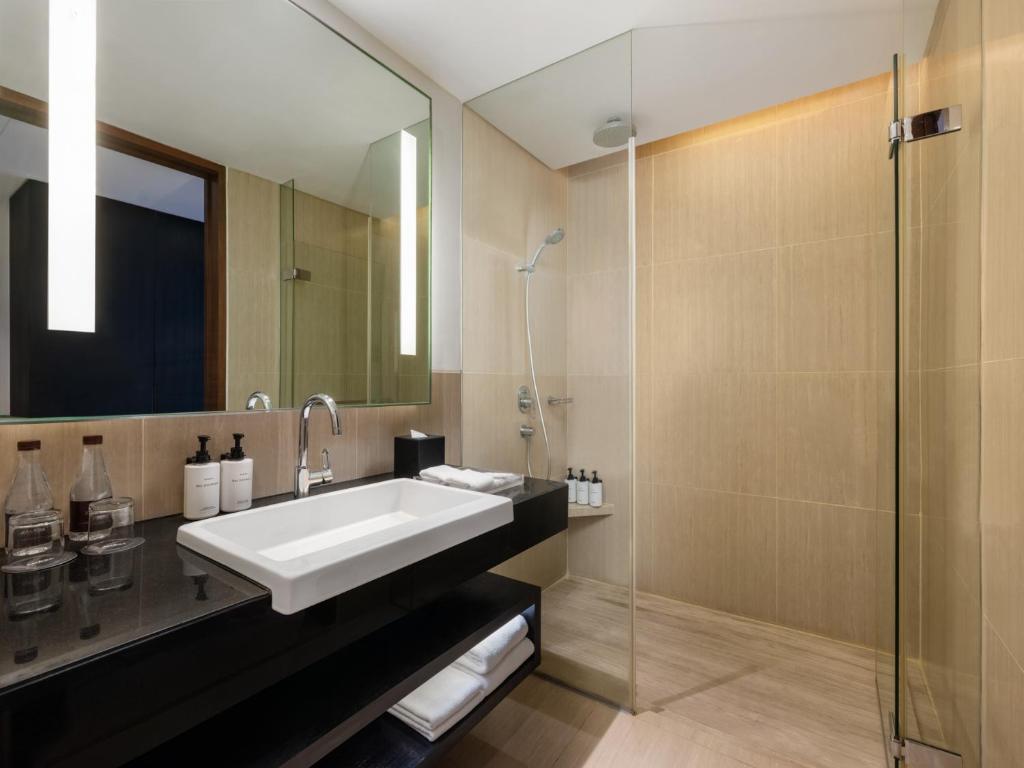 A compact bathroom with a floating vanity and glass walk-in shower.