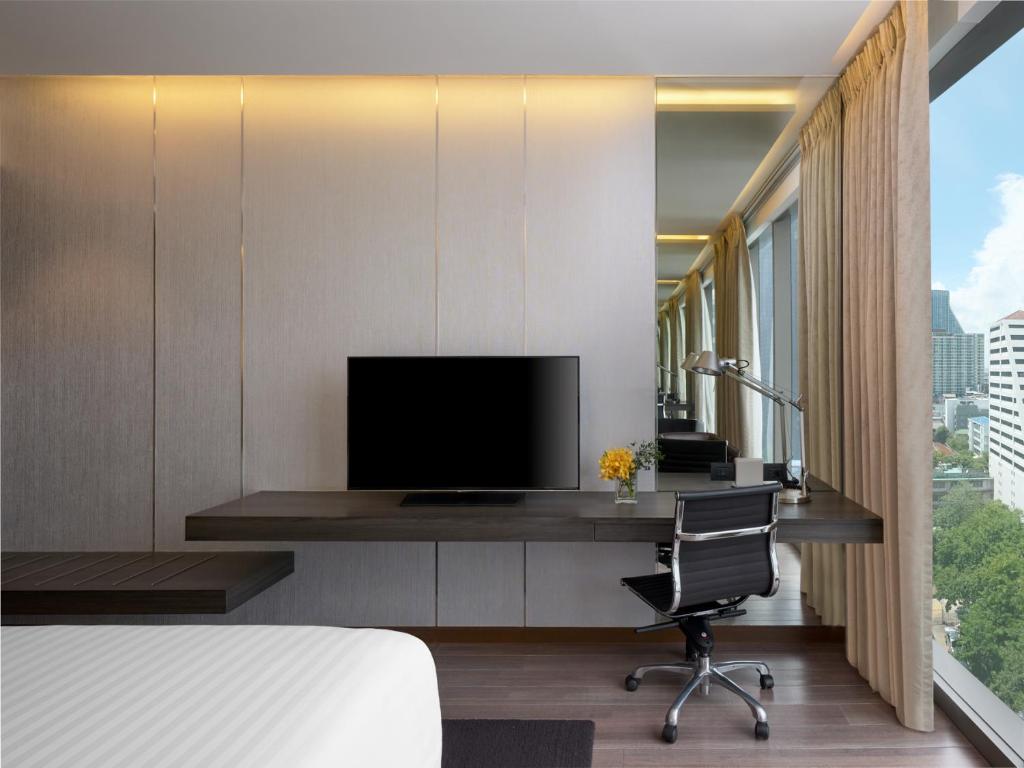 A bedroom workspace beside a TV wall and tall city-facing window.