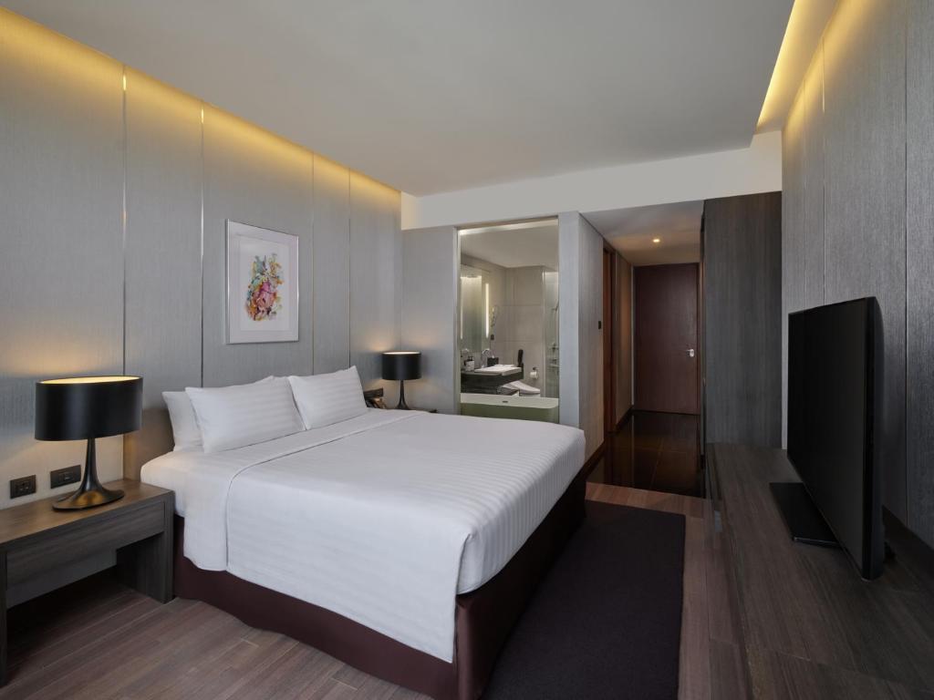 A bedroom photographed from the television side, showing the bathroom entrance and storage area.