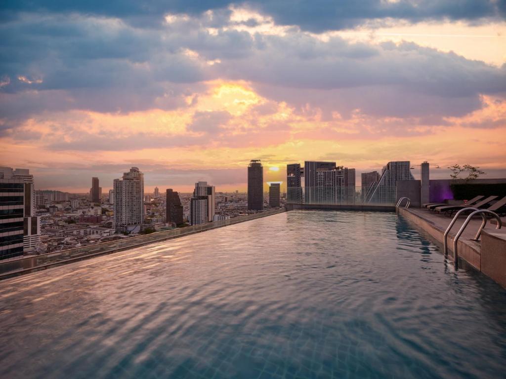 a swimming pool on top of a building with a city at Amara Bangkok Hotel in Bangkok
