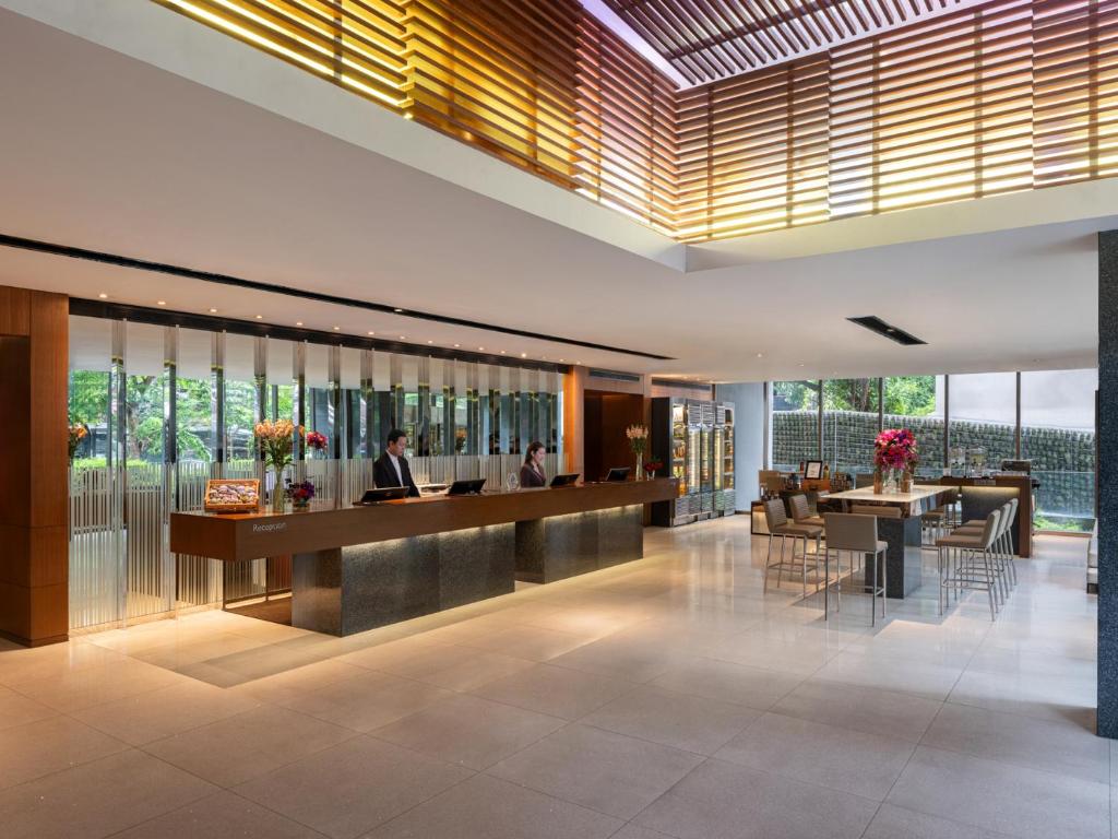 a lobby of a hotel with people sitting at a bar at Amara Bangkok Hotel in Bangkok