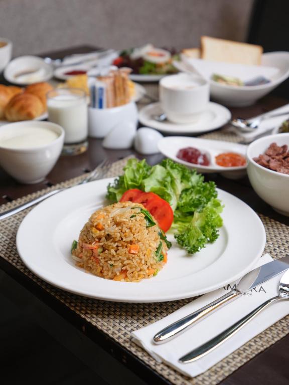 A plated fried-rice breakfast served with fruit and continental accompaniments.
