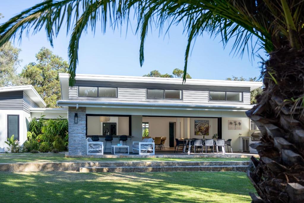 a house with a palm tree in front of it at It's Five O'Clock Somewhere I Private Properties in Yallingup