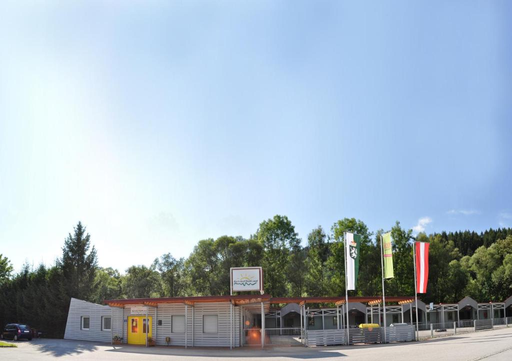 ein kleines Gebäude mit Flaggen auf einem Parkplatz in der Unterkunft Gästedorf Waldheimat in Langenwang
