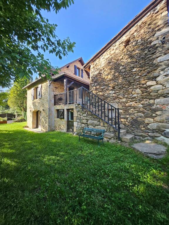 un bâtiment en pierre avec un banc dans l'herbe dans l'établissement Charmante Maisonette du Lot rénovée avec balnéo, à Latouille-Lentillac