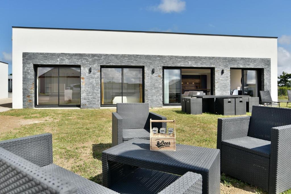 a house with chairs and a table in front of it at Cosy Fréhel - Maison moderne proche du bourg in Frehel
