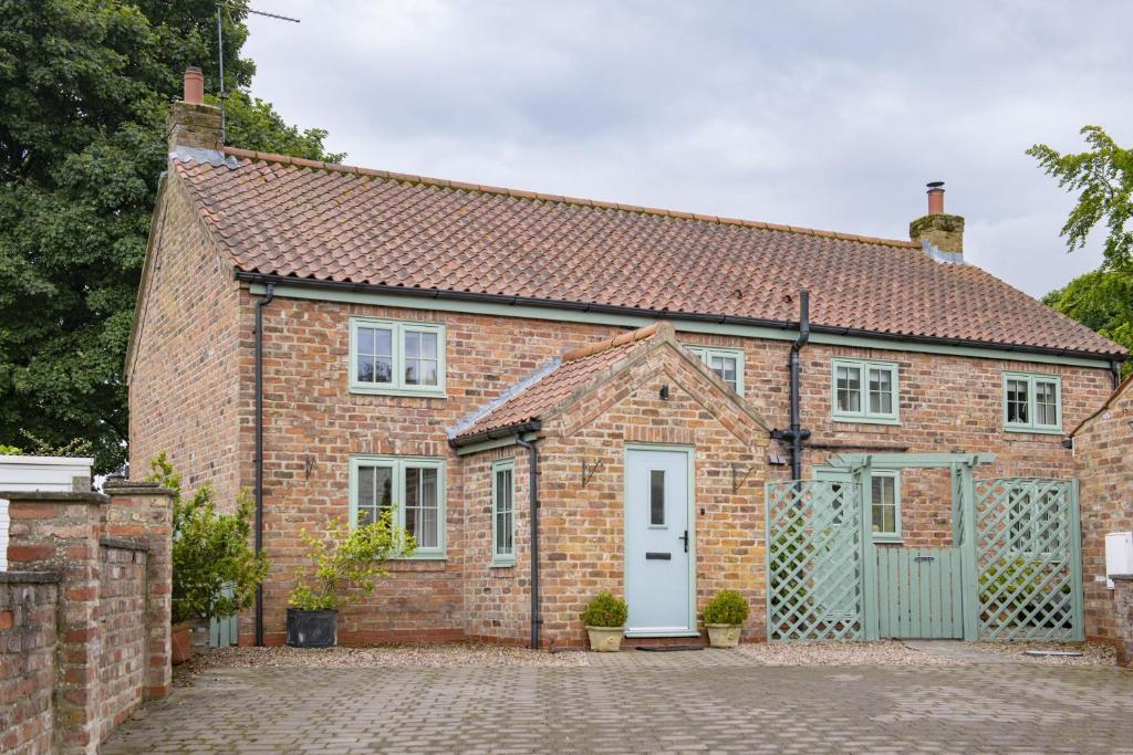 una vecchia casa di mattoni con una porta bianca di Rose Cottage a Huggate