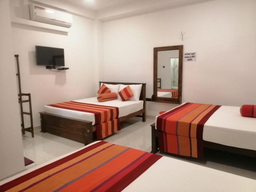 a bedroom with two beds and a tv in it at Golden Residence in Anuradhapura
