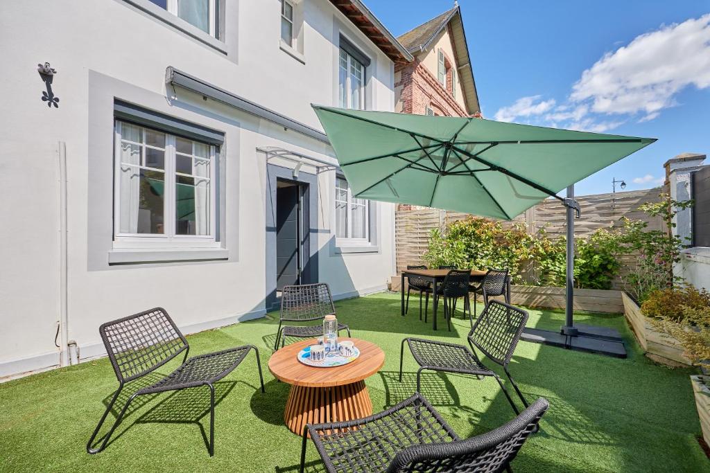 une terrasse avec des chaises et une table avec un parasol vert dans l'établissement La Halte Sainte-Catherine - A 15 min de la plage, à Honfleur