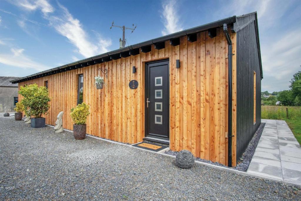a wooden building with a door and some plants at The Shed - 1 Bedroom - Cosheston in Cosheston