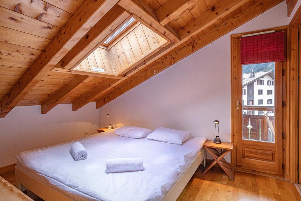 une chambre avec un grand lit blanc avec une fenêtre dans l'établissement Apartment Capucin - A 3 Bedroom Chamonix Mountain Loft, à Chamonix-Mont-Blanc