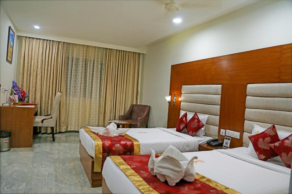 a hotel room with two beds and a desk at Hotel Hyderabad Grand in Shamshabad