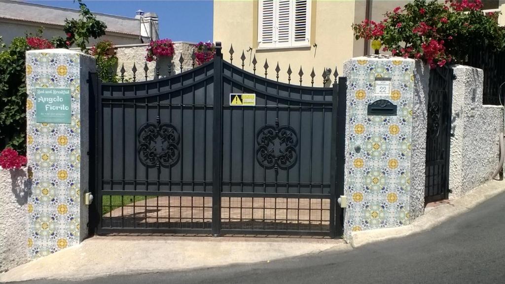 Una puerta de hierro negra con flores. en Bed and Breakfast Angolo Fiorito, en Civitavecchia