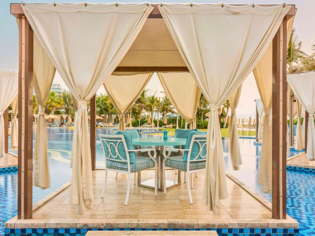 a gazebo with a table and chairs next to a pool at Waldorf Astoria Dubai Palm Jumeirah in Dubai