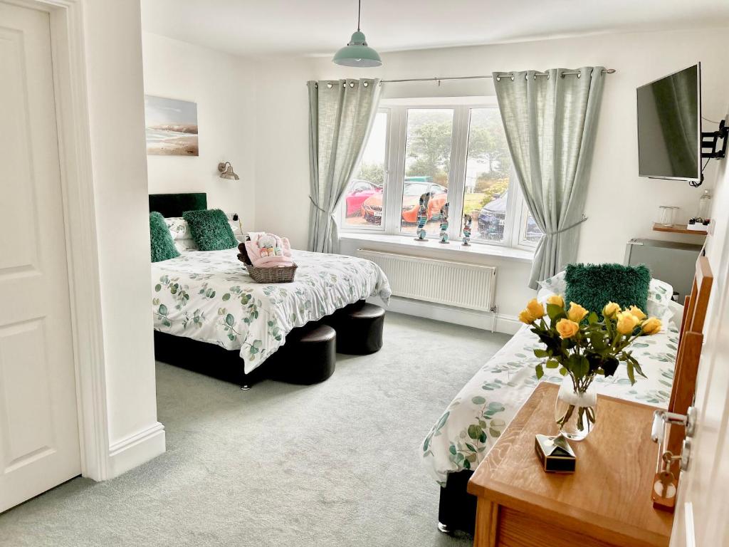 a bedroom with two beds and a table with a vase of flowers at Elysian Fields B&B in Helston