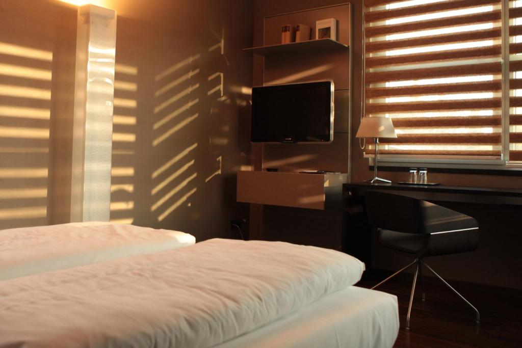 a bedroom with a bed and a desk and a television at Hotel Rosenmeer in Mönchengladbach