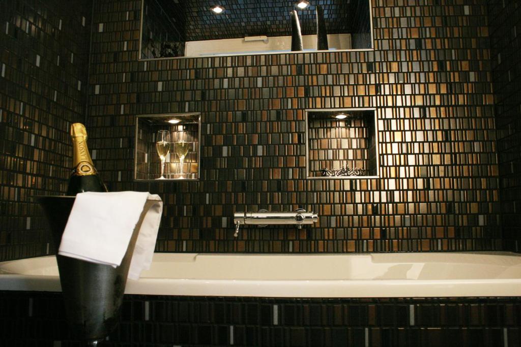 a bathroom with a tub and a bottle of champagne at Hotel Rosenmeer in Mönchengladbach