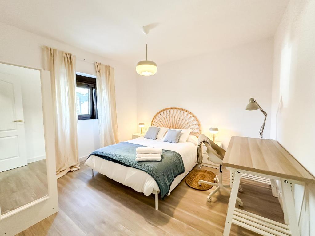 um quarto com uma cama, uma mesa e uma escrivaninha em A Casa de Canosiña by ALÔGA em Fisterra