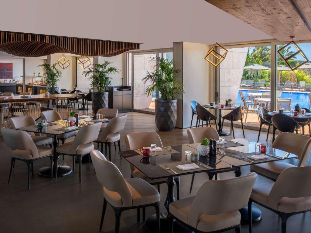 a restaurant with tables and chairs and a pool at Swissôtel Resort Bodrum Beach in Turgutreis