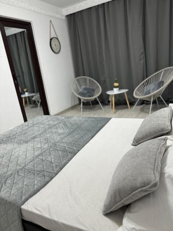 a bedroom with a bed with chairs and a clock at Oly Apartment in Năvodari