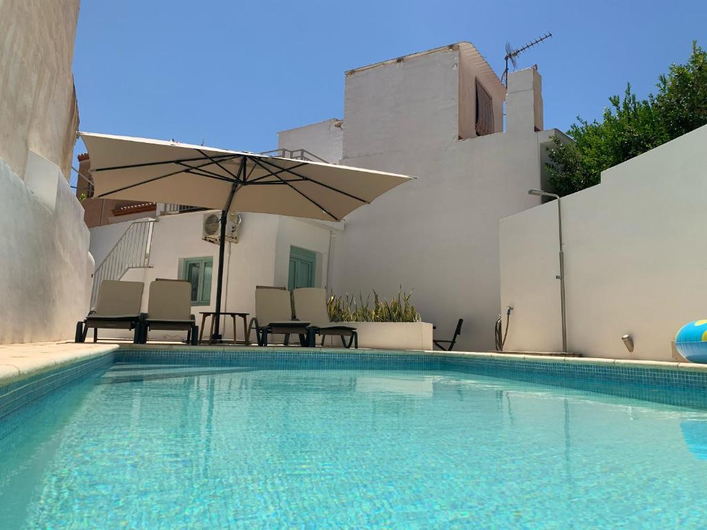 a swimming pool with chairs and an umbrella at Beautiful home with private pool in Vélez de Benaudalla