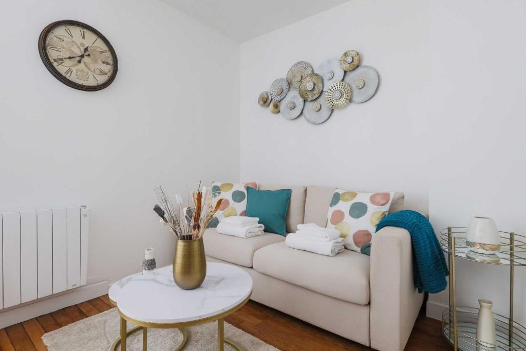un salon avec un canapé et une horloge au mur dans l'établissement Cosy and chic apartment -1BD-4P- Auteuil, à Paris