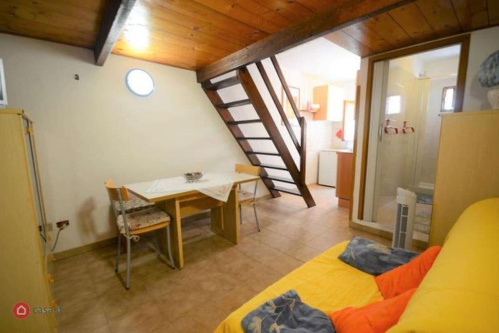 Habitación con cama, mesa y escalera. en Monolocale Dina's House, en Alghero