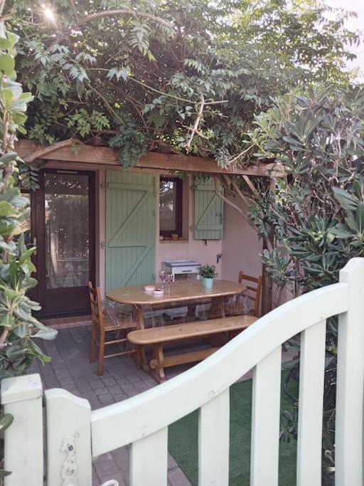 une table et un banc sur une terrasse couverte avec une clôture dans l'établissement Jolie maisonnette dans résidence calme avec piscine, au Barcarès
