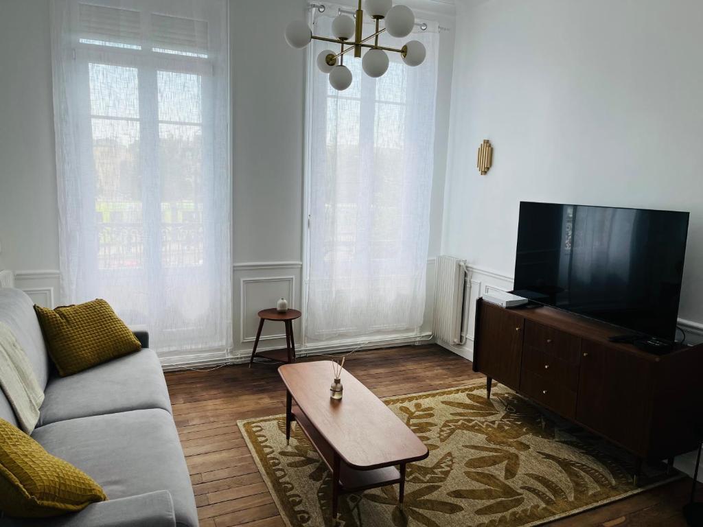 a living room with a couch and a flat screen tv at Appartement Porte Mars 1 Reims Arena gare centre in Reims