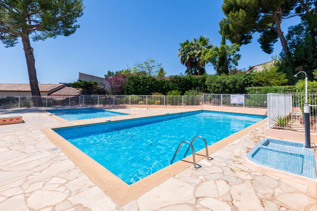 - une piscine dans une cour avec des arbres et une clôture dans l'établissement Appartement Vistamare - Welkeys, à Bandol