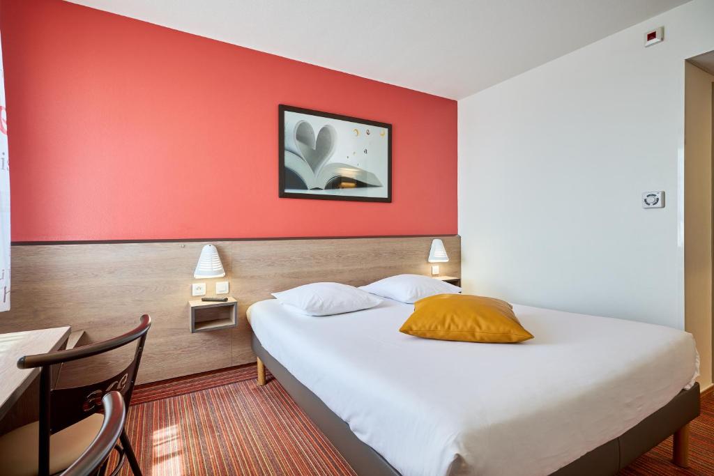a bedroom with a bed with a red wall at Ace Hôtel Caen Nord Mémorial in Caen