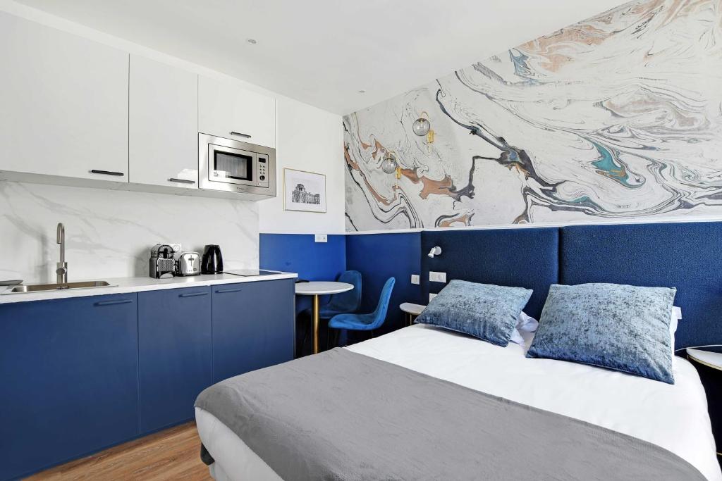 - une chambre bleue et blanche avec un lit et une cuisine dans l'établissement Modern Sutdio for 2 with A-C - Near Montmartre, à Paris