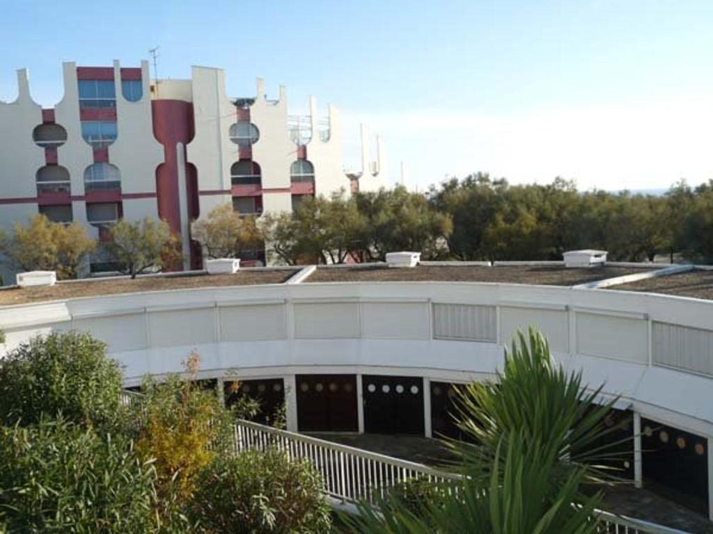 un bâtiment blanc avec un tas de tours en arrière-plan dans l'établissement Studio cabine proche plage, parking privé - FR-1-328-143, à La Grande Motte