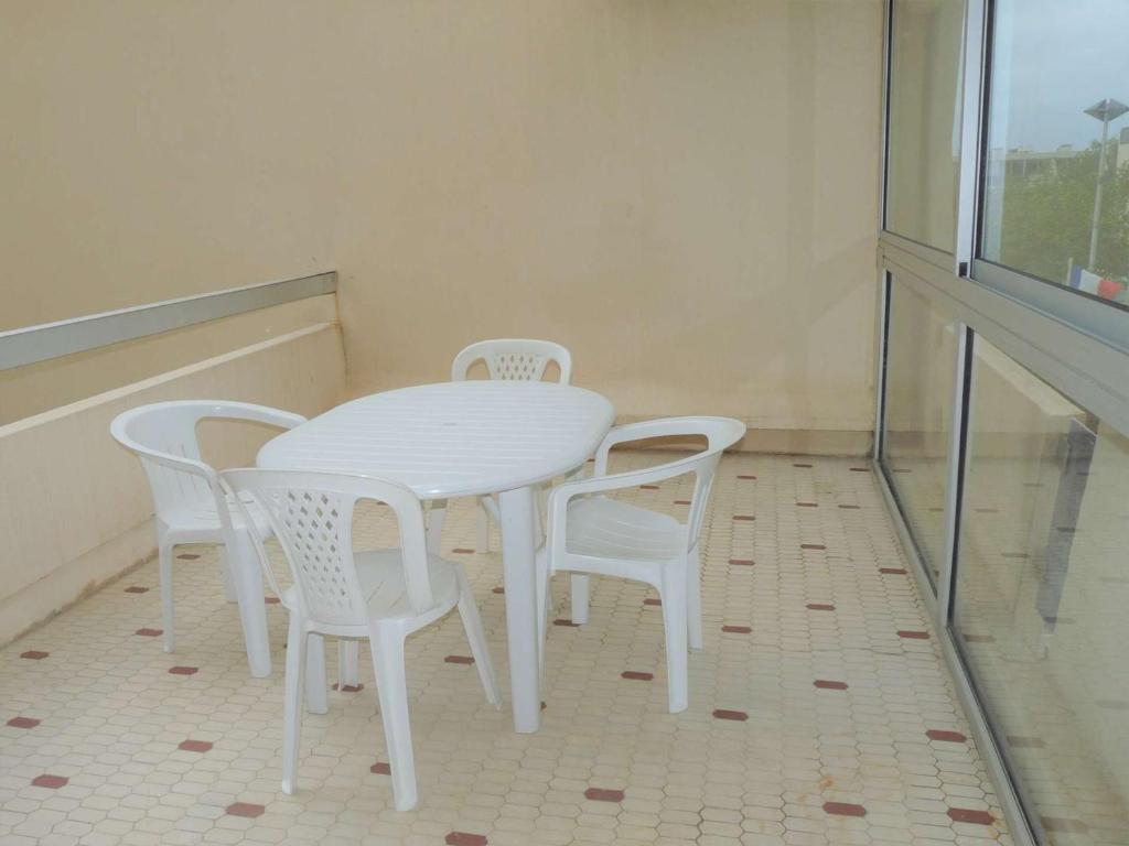 une table blanche et des chaises dans une pièce avec une fenêtre dans l'établissement Studio avec Loggia, Terrasse & Parking Privé en Centre-Ville, Proche Plage - FR-1-328-99, à La Grande Motte