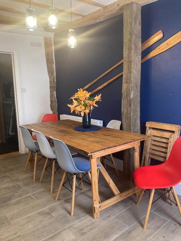 a dining room with a wooden table and chairs at Lime Tree Cottage in Tillingham