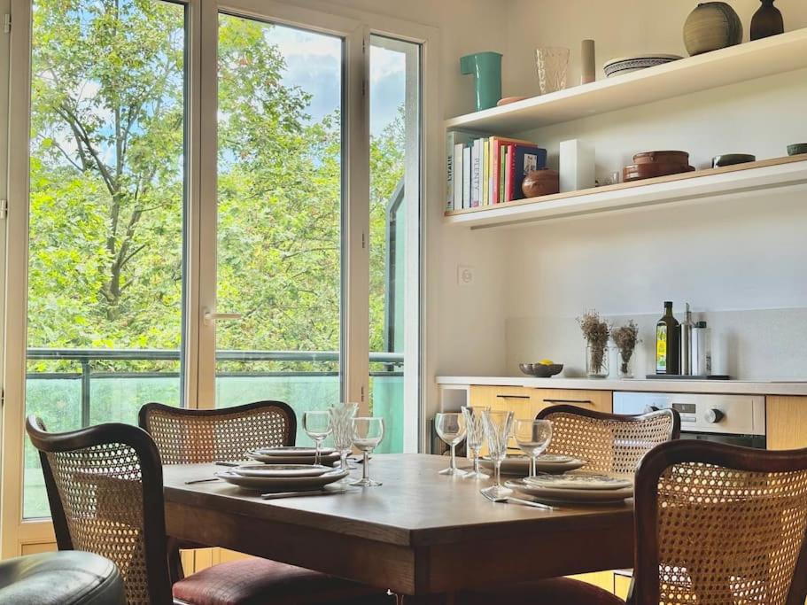 une salle à manger avec une table et des verres à vin dans l'établissement Magnifique appartement - Parc des Buttes Chaumont, à Paris