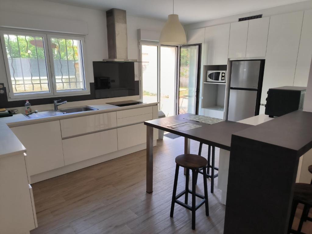 une cuisine avec des placards blancs et une table avec un tabouret dans l'établissement Appartement pour 2 personnes Mauguio centre, à Mauguio