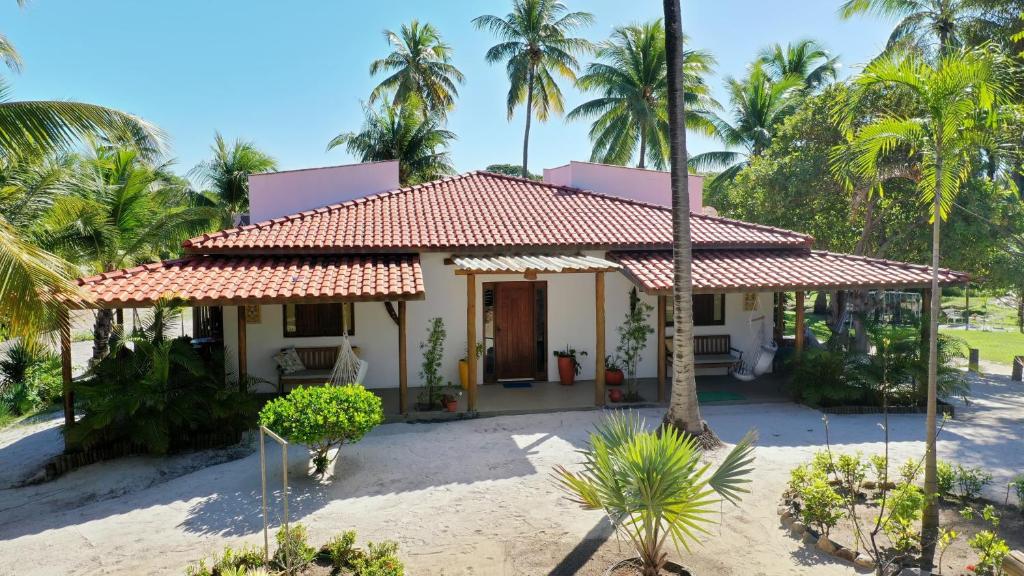 a house on the beach with palm trees at Recanto Verde - Praia de Santo Antônio in Diogo