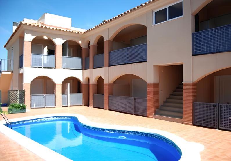 a villa with a swimming pool in front of a building at Acogedor apartamento cerca de la playa wifi y parking in Montroig