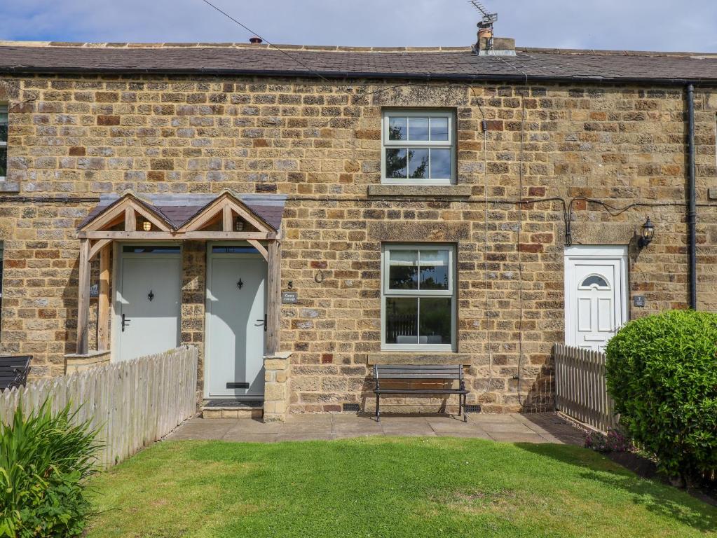 a brick house with a bench in front of it at Canny Cottage in Belford
