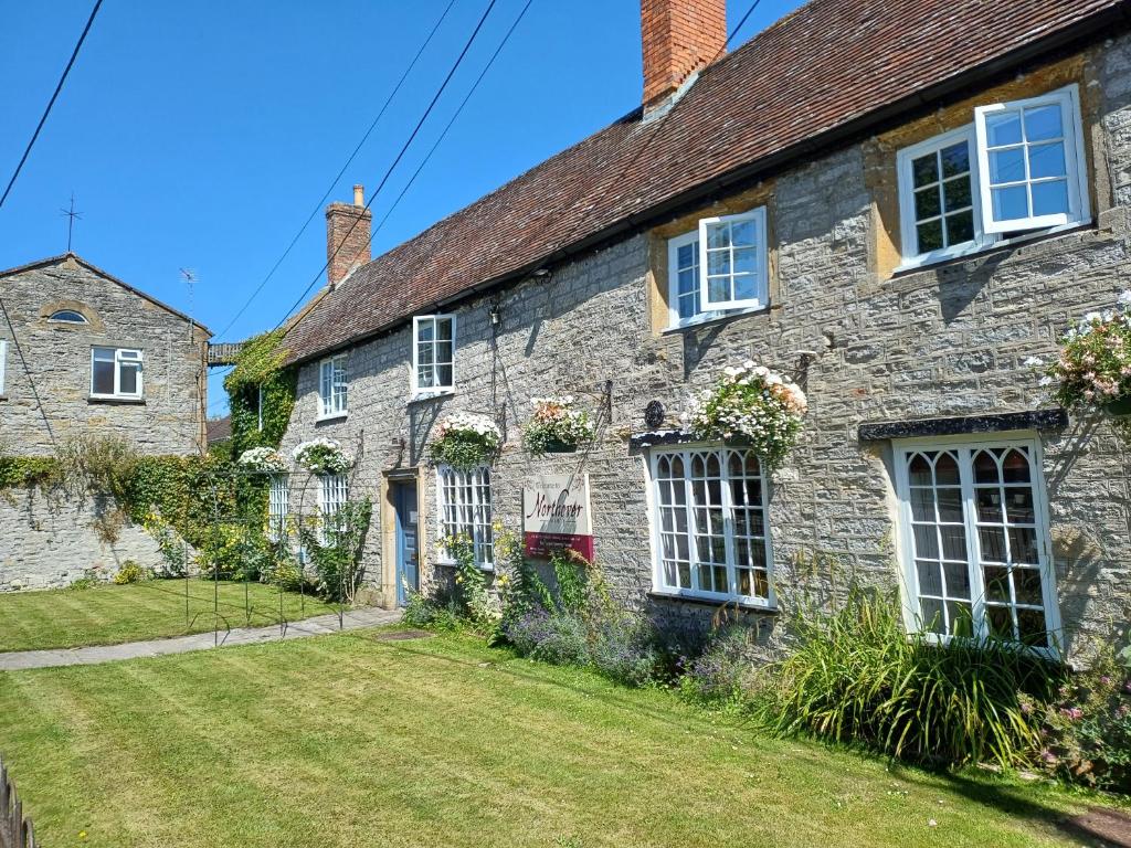 an old stone house with flowers on the windows at Northover Manor Hotel in Ilchester