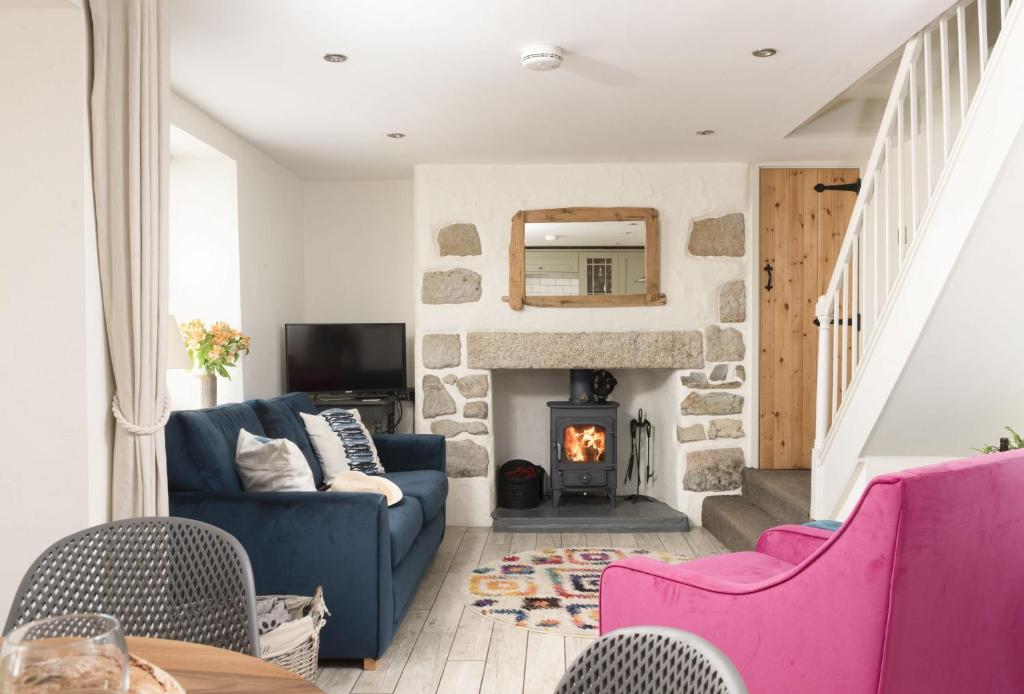 a living room with a blue couch and a fireplace at Oriel Cottage in St. Agnes