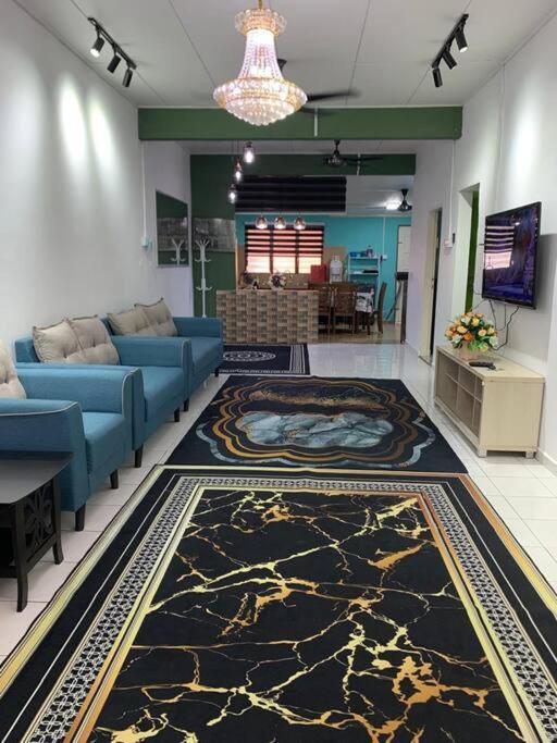 a living room with a blue couch and a rug at Mohan Homestay in Kuala Terengganu