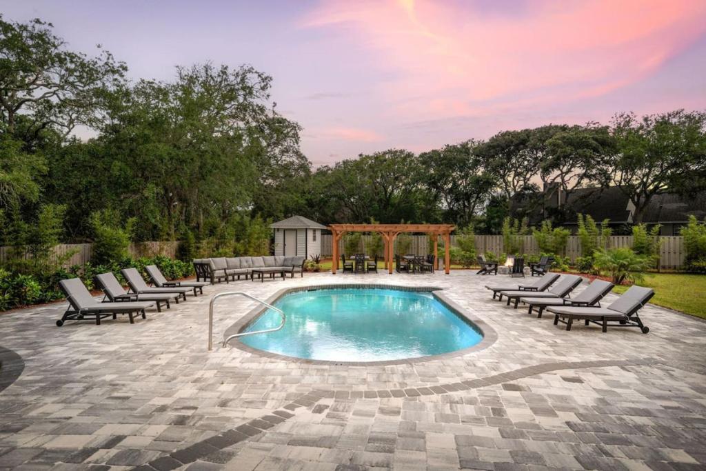 a swimming pool with lounge chairs and a gazebo at Vilano Rose Slps 24, 6Bds, 5 Bths, Pool, Wlk to Beach, Golf, Pets in Saint Augustine