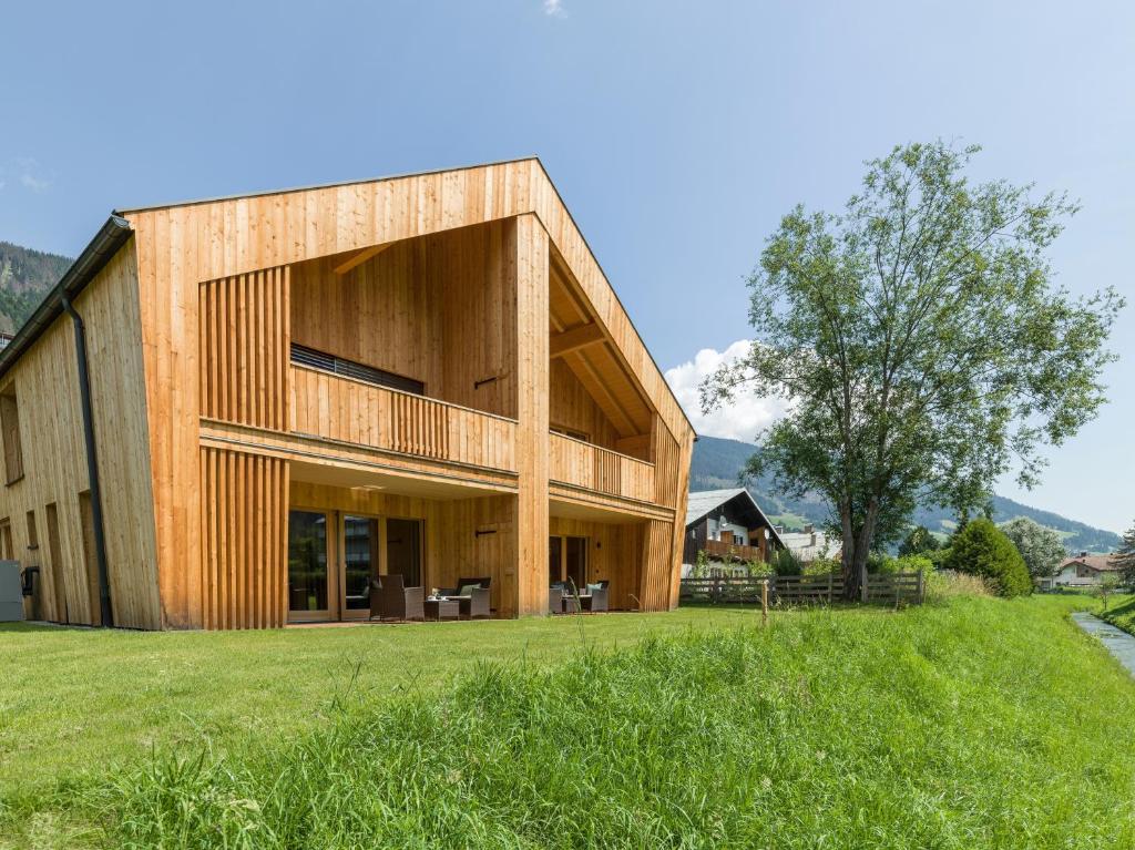 a wooden house on a hill with a green field at Chalet Refugium Dolomiten in Sillian